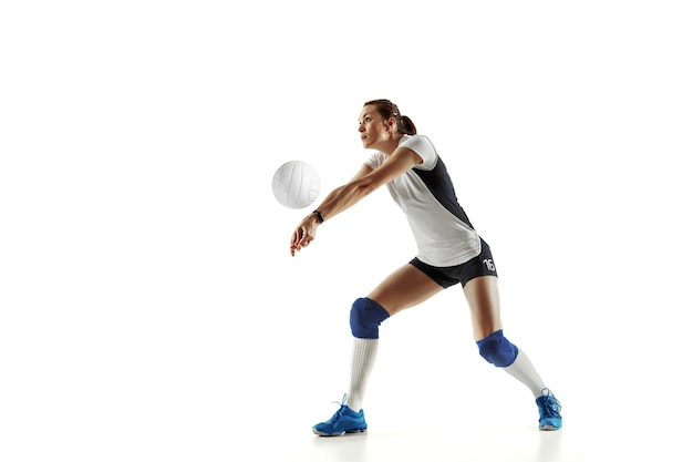 Jugador de voleibol femenino joven aislado sobre fondo blanco de estudio. Mujer en equipamiento deportivo y zapatos o zapatillas de deporte entrenando y practicando. Concepto de deporte, estilo de vida saludable, movimiento y movimiento.