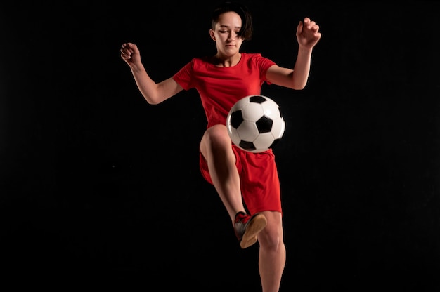Foto gratuita jugadora saltando y pateando la pelota