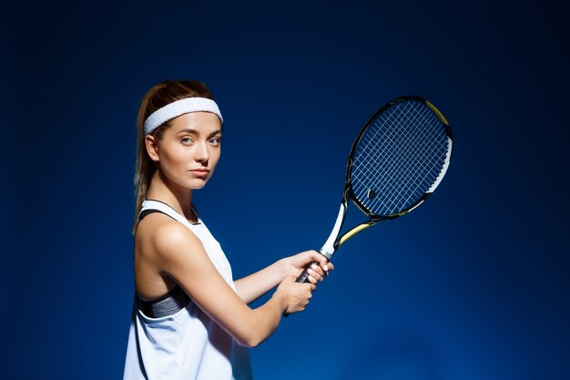 Jugadora de tenis con raqueta lista para golpear una pelota.