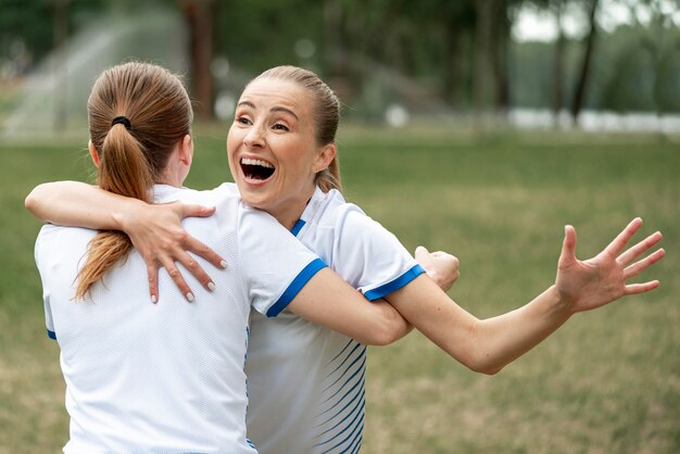 Jugadores de equipo de tiro medio abrazándose