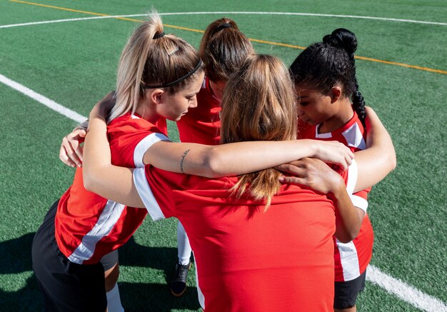 Jugadores de fútbol de tiro medio abrazados