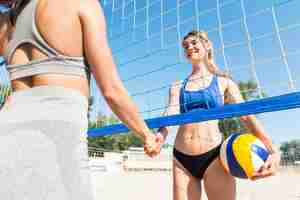 Foto gratuita jugadores de voleibol femenino estrecharme la mano debajo de la red