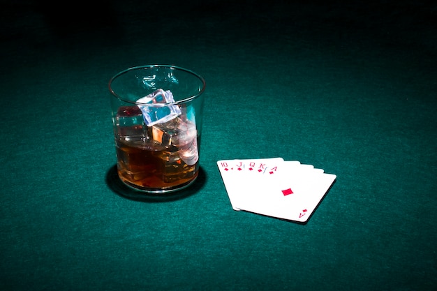 Jugando a las cartas y vaso de whisky en la mesa verde