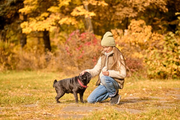 Jugando con un perro. Una niña en ropa de abrigo jugando con un perro en el parque.
