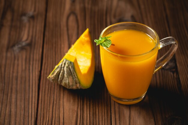 Jugo de calabaza fresca en vidrio en la mesa de madera.