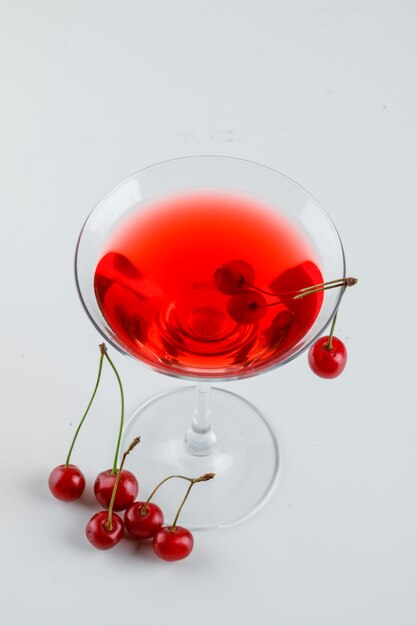 Jugo de cereza con cerezas en un vaso en blanco