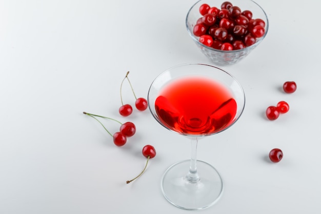 Jugo de cereza con cerezas en un vaso en blanco