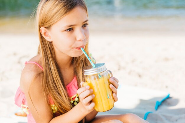 Jugo de consumición de la muchacha linda en la playa