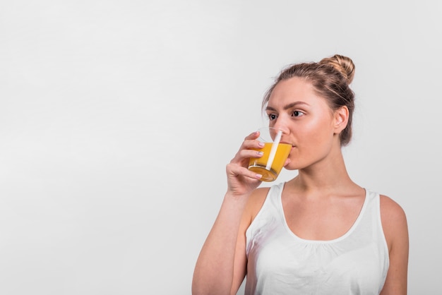 Jugo de consumición de la mujer joven del vidrio