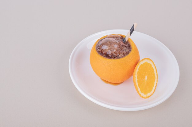Jugo dentro de naranja en plato blanco.