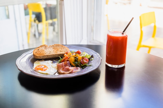 Jugo; Desayuno fresco en un plato gris sobre la mesa negra.