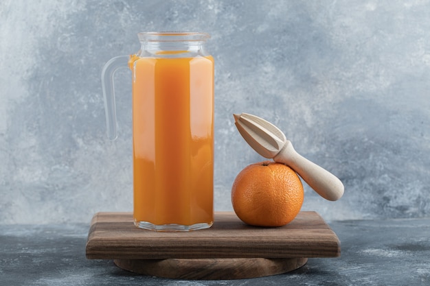 Jugo fresco y naranja con escariador sobre tabla de madera.