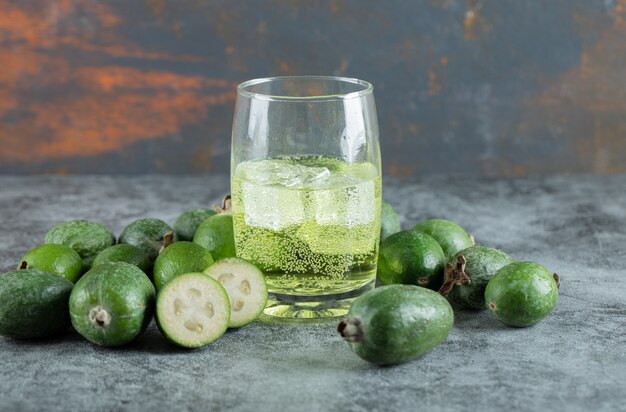 Jugo frío y frutas feijoa sobre mesa de mármol.