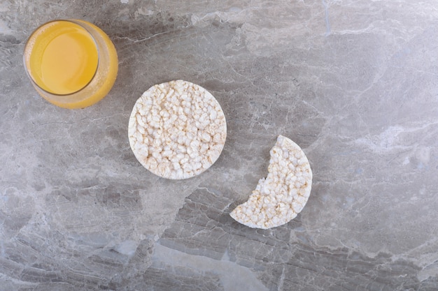 Jugo de fruta junto a tortas de arroz inflado, sobre la superficie de mármol