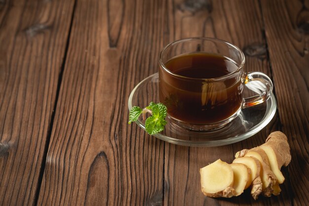 El jugo de jengibre caliente y el jengibre en rodajas en la mesa de madera.