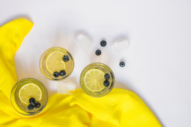 Jugo de limón con arándanos y cubitos de hielo sobre fondo blanco