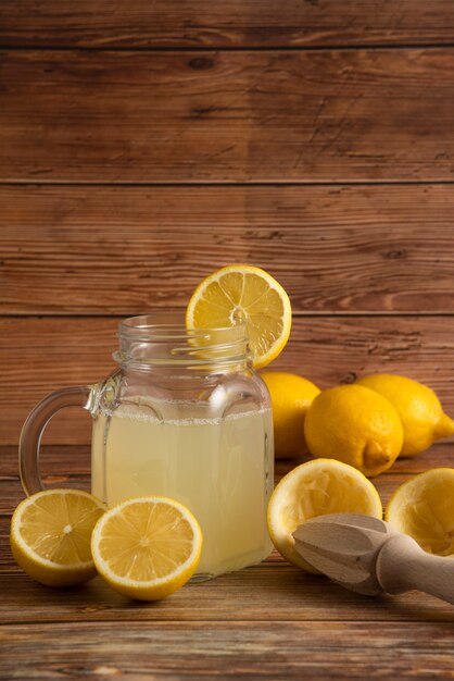 Jugo de limón en el recipiente de vidrio con frutas sobre la mesa de madera