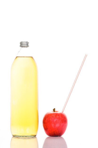 Jugo de manzana en una botella de vidrio y manzana con pajita