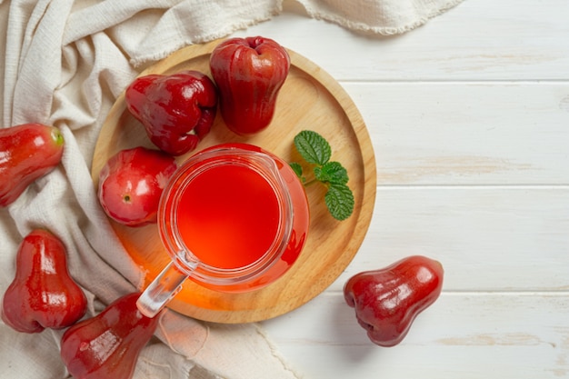 Jugo de manzana rosa sobre superficie de madera blanca