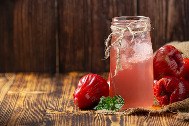 Jugo de manzana rosa sobre superficie de madera oscura.