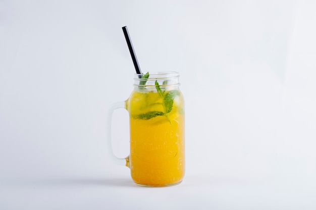 Jugo de naranja amarillo en un frasco de vidrio con hojas de menta.