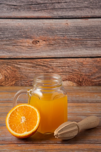 Foto gratuita jugo de naranja en un frasco de vidrio sobre la mesa de madera