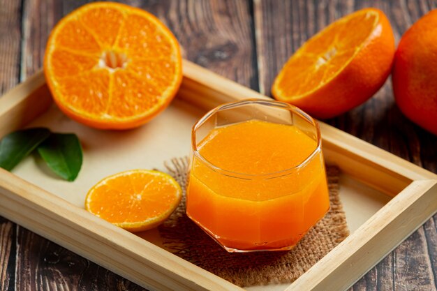 Jugo de naranja fresco en el vaso sobre fondo de madera oscura.