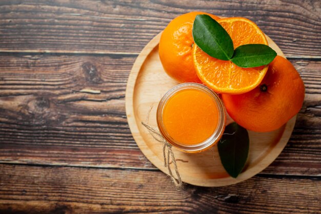 Jugo de naranja fresco en el vaso sobre fondo de madera oscura.