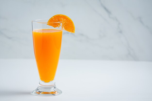 Jugo de naranja fresco en el vaso sobre fondo de mármol