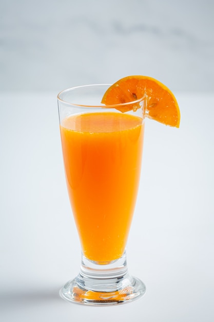 Jugo de naranja fresco en el vaso sobre fondo de mármol