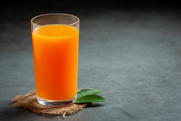 Jugo de naranja fresco en el vaso sobre fondo oscuro