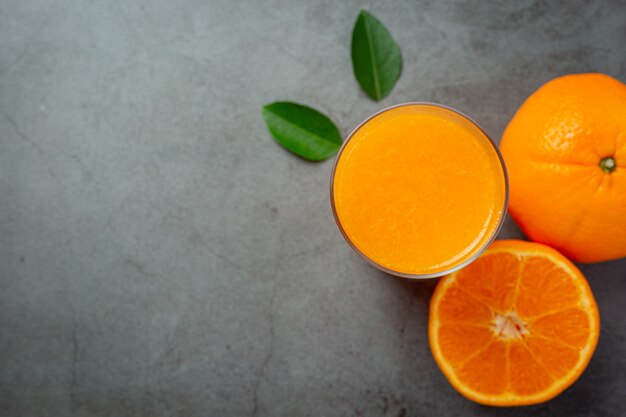 Jugo de naranja fresco en el vaso sobre fondo oscuro