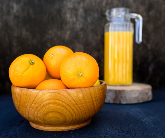 Foto gratuita jugo de naranja y pila de naranjas en un tazón