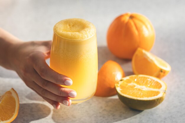 Jugo de naranja recién exprimido en manos femeninas de cerca