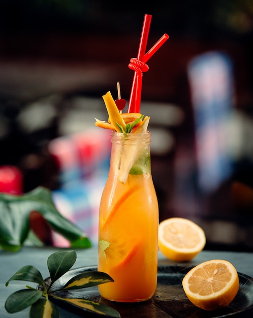 jugo de naranja con rodajas de naranja y pipas rojas en botella