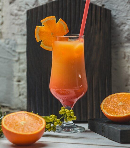 Jugo de naranja con rodajas en un vaso con tubo rojo.