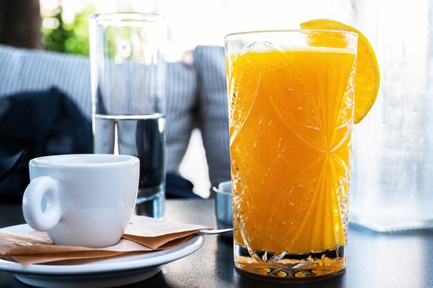 Jugo de naranja y una taza de café en un restaurante.