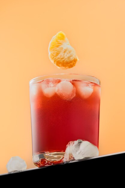 Foto gratuita jugo o cóctel de cítricos frescos. rebanada de mandarina voladora sobre un vaso. enfoque selectivo en la levitación de la rebanada de fruta. la idea de hacer un cóctel o jugo con una mandarina.