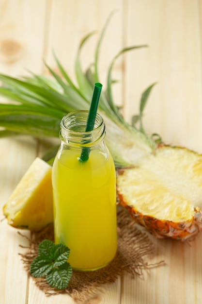 Jugo de piña en botella sobre superficie de madera