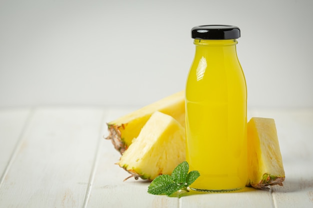 Jugo de piña sobre superficie de madera blanca