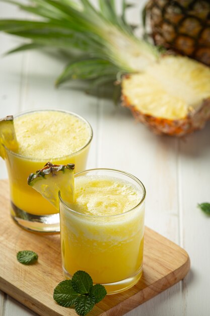 Jugo de piña sobre superficie de madera blanca