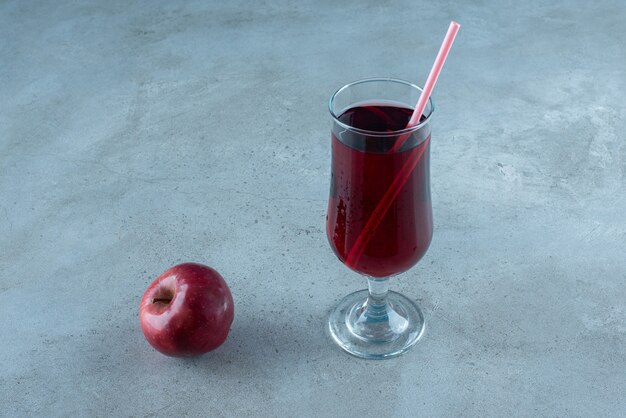 Jugo rojo sabroso con manzana fresca y paja.