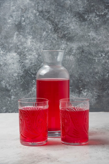 Foto gratuita jugo rojo en vasos y tarro.