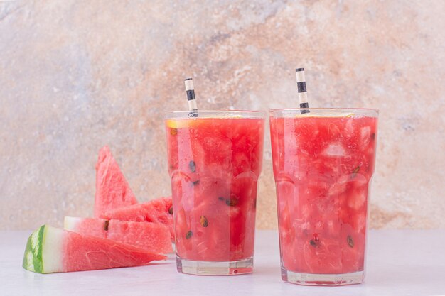 Jugo de sandía con rodajas de frutos rojos sobre fondo blanco.