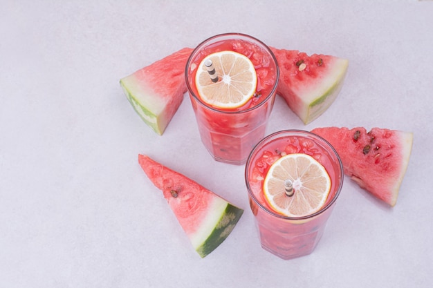 Jugo de sandía con rodajas de frutos rojos sobre fondo blanco.