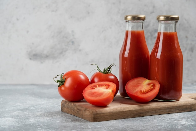 Jugo de tomate en frascos de vidrio sobre una tabla de madera.