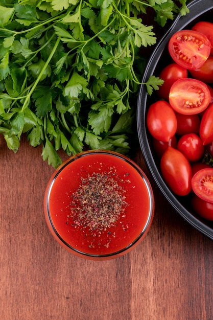 Foto gratuita jugo de tomate en vidrio y tomates cherry en vista superior de pan