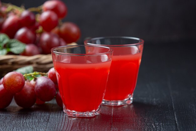 Jugo de uva fresco en la superficie de madera oscura.