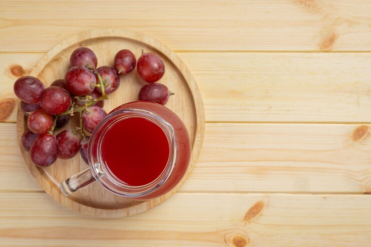 Foto gratuito jugo de uva fresco en la superficie de madera.
