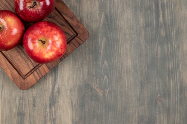 Jugosas manzanas rojas sobre una tabla de cortar de madera. Foto de alta calidad